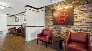 A Red Roof Inn lobby with a stone wall, leather chairs, and a reception desk. - Red Roof Inn Gurnee - Waukegan (Waukegan)