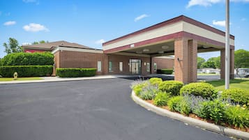 A gas station with a brick building, a covered fuel pump area, and a parking lot.