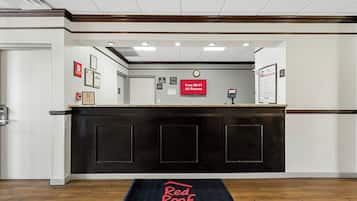 A hotel reception area with a check-in counter, a clock, and a Red Roof Inn sign.