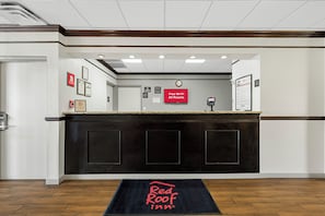 Recepção de hotel com balcão de check-in, relógio e placa da Red Roof Inn.