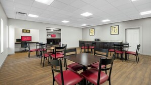 A conference room with a long table, multiple chairs, a kitchenette, and a sign indicating free Wi-Fi in all rooms. - Red Roof Inn Gurnee - Waukegan (Waukegan)