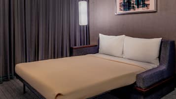 A hotel room with a bed, a nightstand, a lamp, and a painting on the wall.