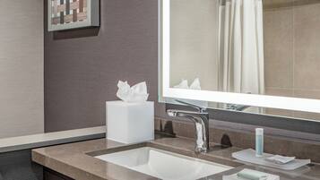 A modern bathroom with a large mirror, a sink, and a towel dispenser.