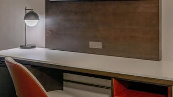A modern office desk with a lamp, a chair, and a TV mounted on the wall.