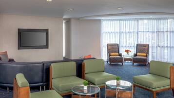 A modern lounge area with a sofa, armchairs, and a flat-screen TV mounted on the wall.