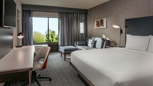 A hotel room with a large bed, a desk with a chair, a sofa, and a TV. - Courtyard by Marriott Boston Marlborough (Marlborough)