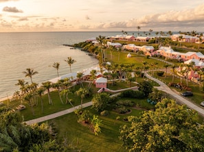 A coastal resort with multiple pink-roofed buildings, palm trees, and a view of the ocean. - Cambridge Beaches Resort & Spa (Sandys Parish)