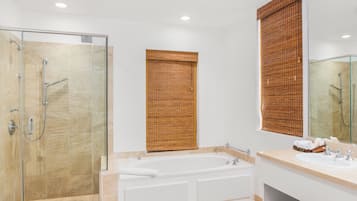 A modern bathroom with a glass-enclosed shower, a freestanding bathtub, and a vanity with a mirror.