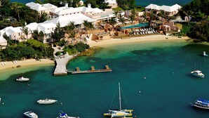 An aerial view of a coastal resort with multiple buildings, a beach, and boats in the water.