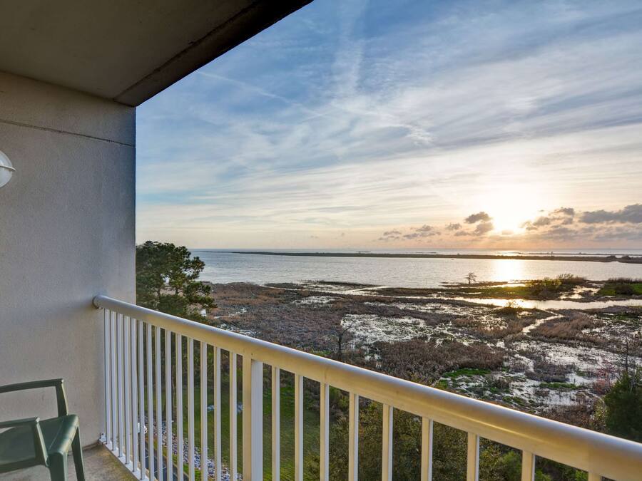 A balcony with a view of a coastal landscape during sunset.