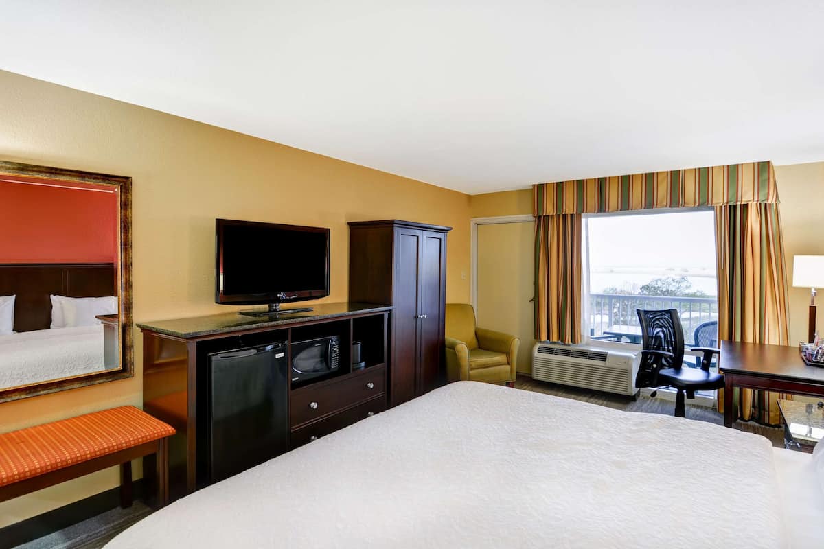 A hotel room with a bed, a TV, a desk, a chair, and a window with curtains.