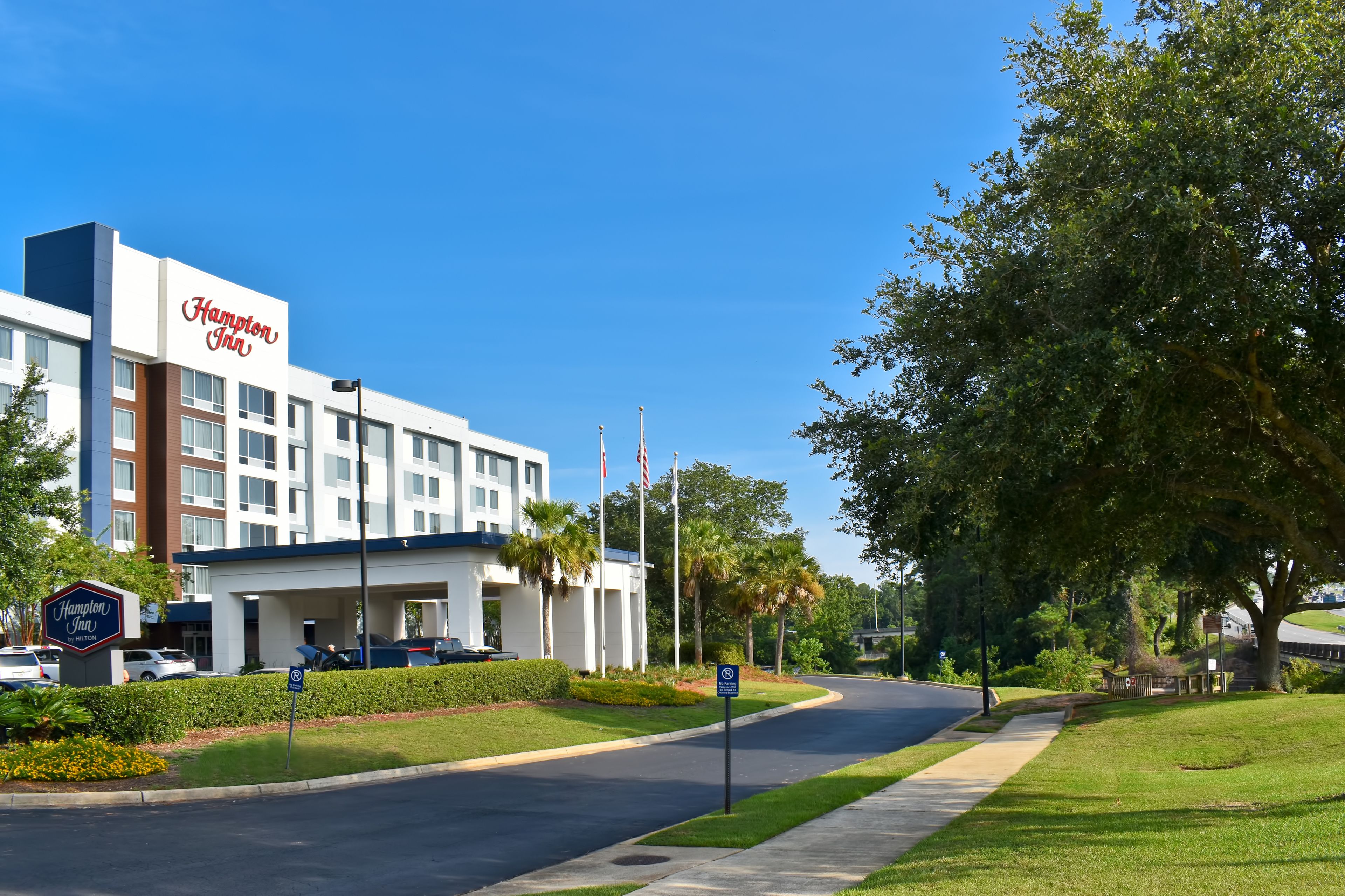 Un hotel Hampton Inn con diseño moderno, estacionamiento y un césped bien cuidado.