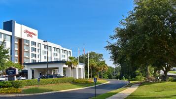 Un hotel Hampton Inn con diseño moderno, estacionamiento y un césped bien cuidado.