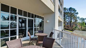 A balcony with outdoor seating, large windows, and a view of trees.