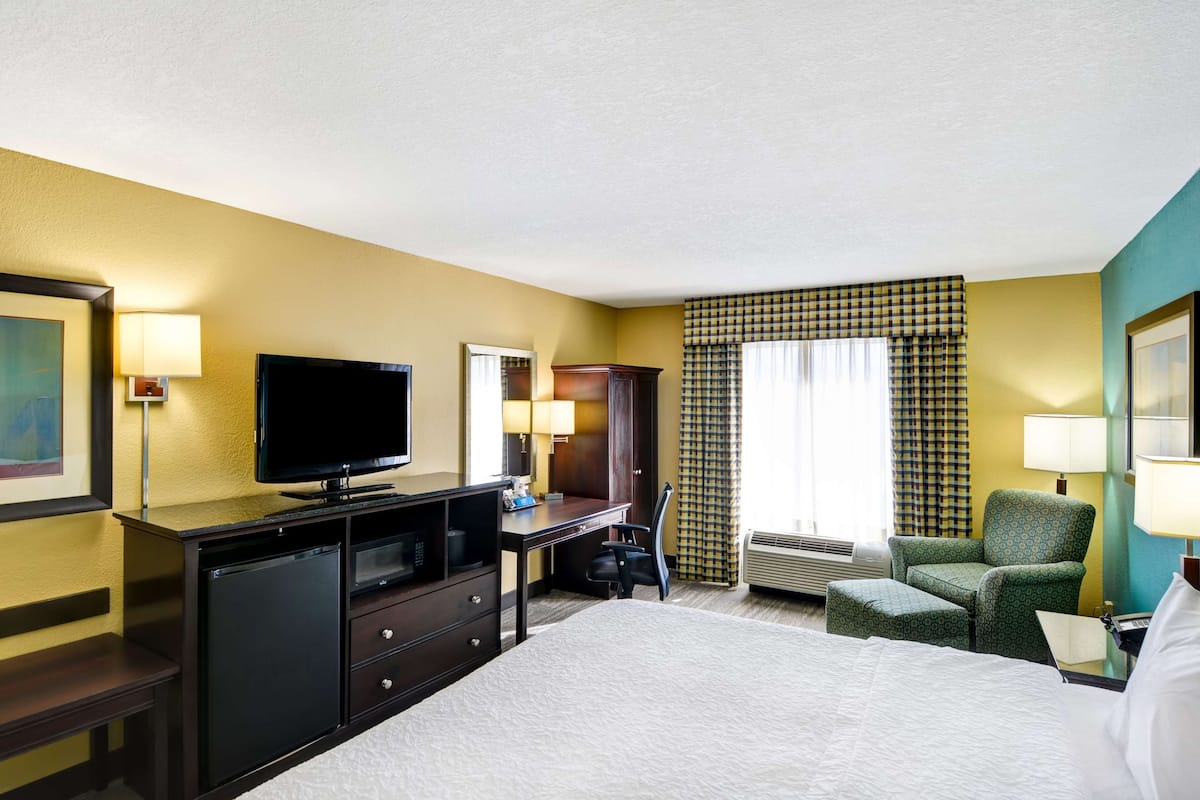 A hotel room with a bed, a desk with a computer, a television, and a chair.
