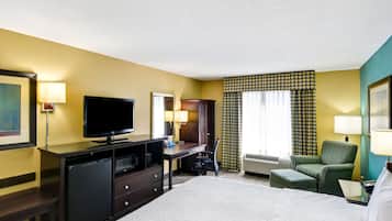 A hotel room with a bed, a desk with a computer, a television, and a chair.