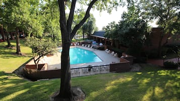 Una piscina al aire libre, sombrillas, sillones reclinables de piscina