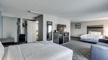 Ein Hotelzimmer mit einem großen Bett, einem Schreibtisch mit Computer, einem Stuhl, einem Kleiderschrank und einem Nachttisch.
