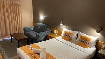 Relax in this stylish room featuring a comfortable bed with a bold bedspread, a cozy armchair, and a small table.