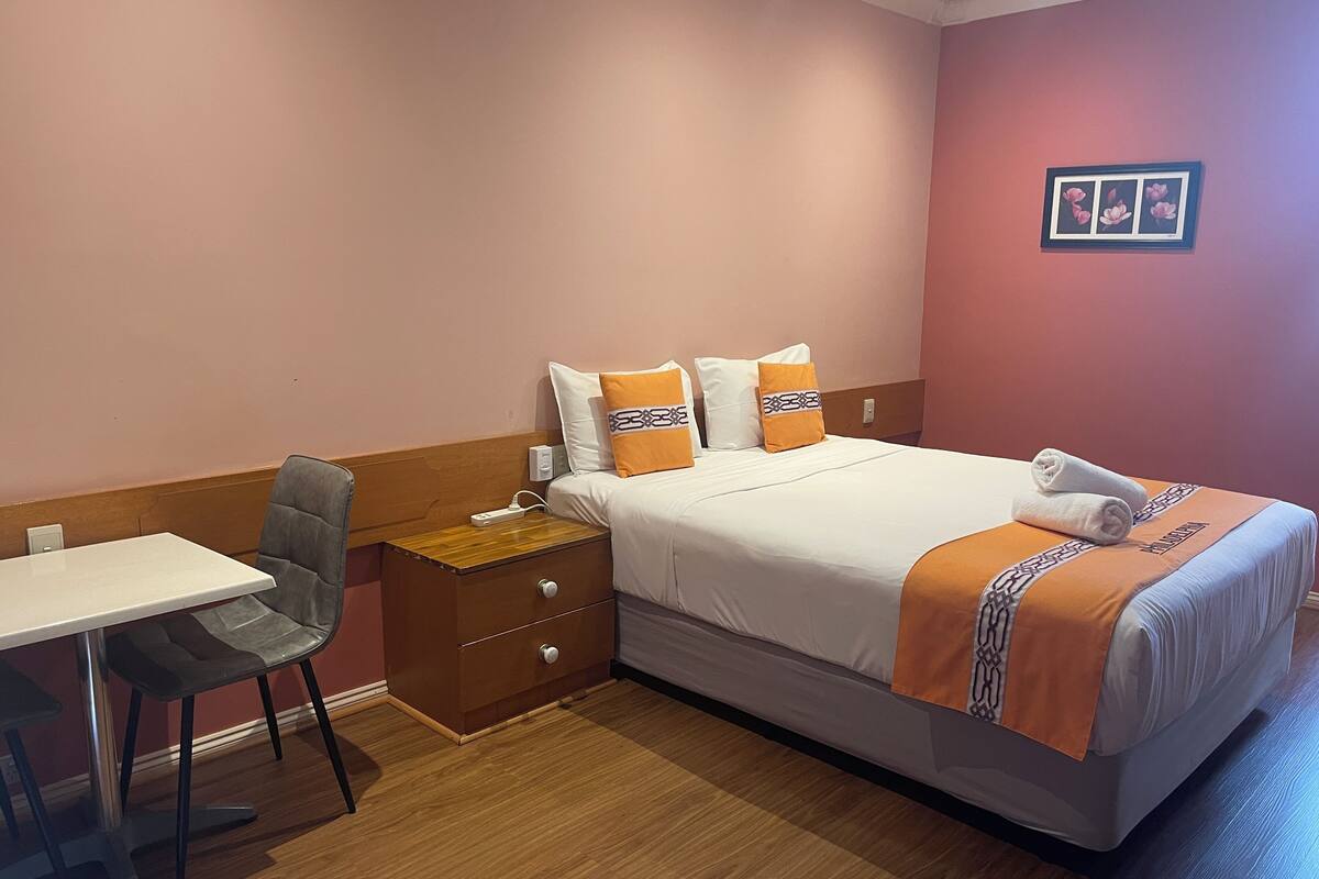 A hotel room with a bed, a desk, and a chair.