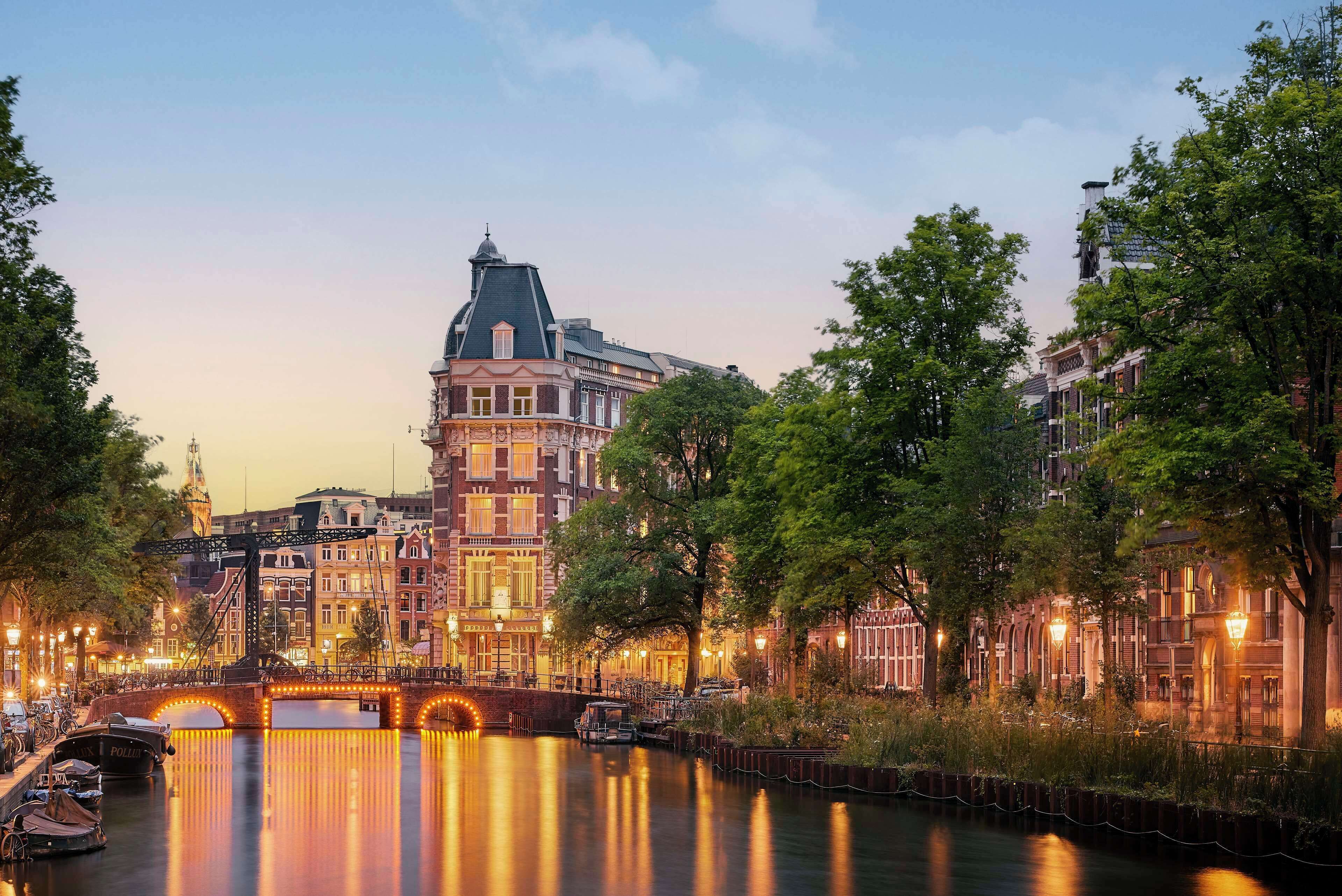 Un canal con un puente, edificios históricos y árboles a lo largo de sus orillas.
