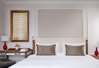 A hotel room with a bed, bedside tables, a desk, and a large framed artwork on the wall.