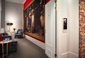 A hallway with a large classical painting, a modern lamp, a sofa, and a door marked with the number 105.