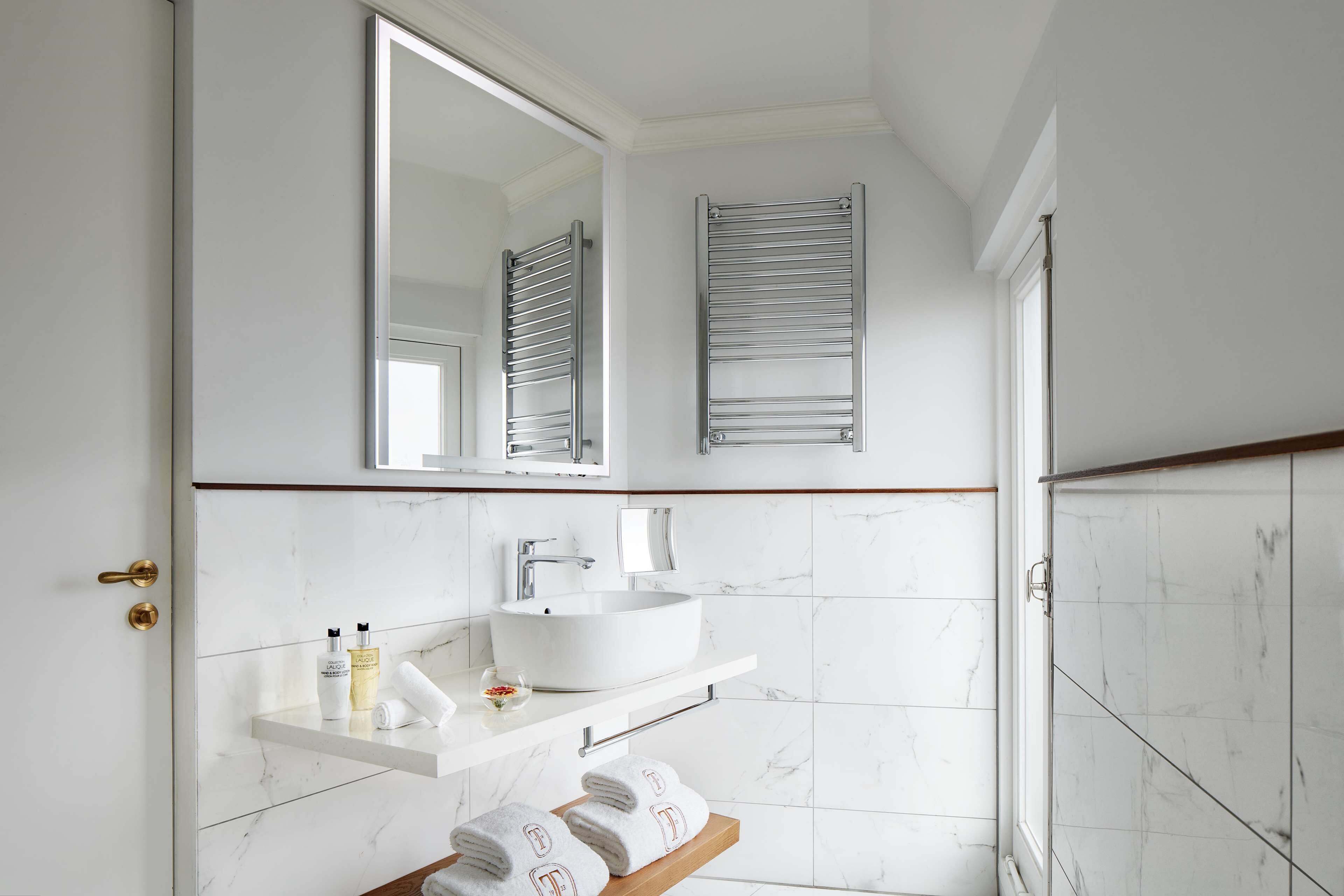 A bathroom with a white sink, mirror, towel rack, and a shower area.