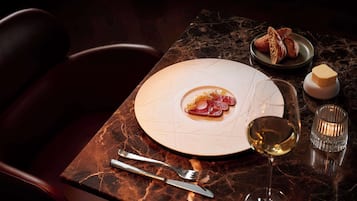 A dining table with a plate of food, a glass of wine, and cutlery.
