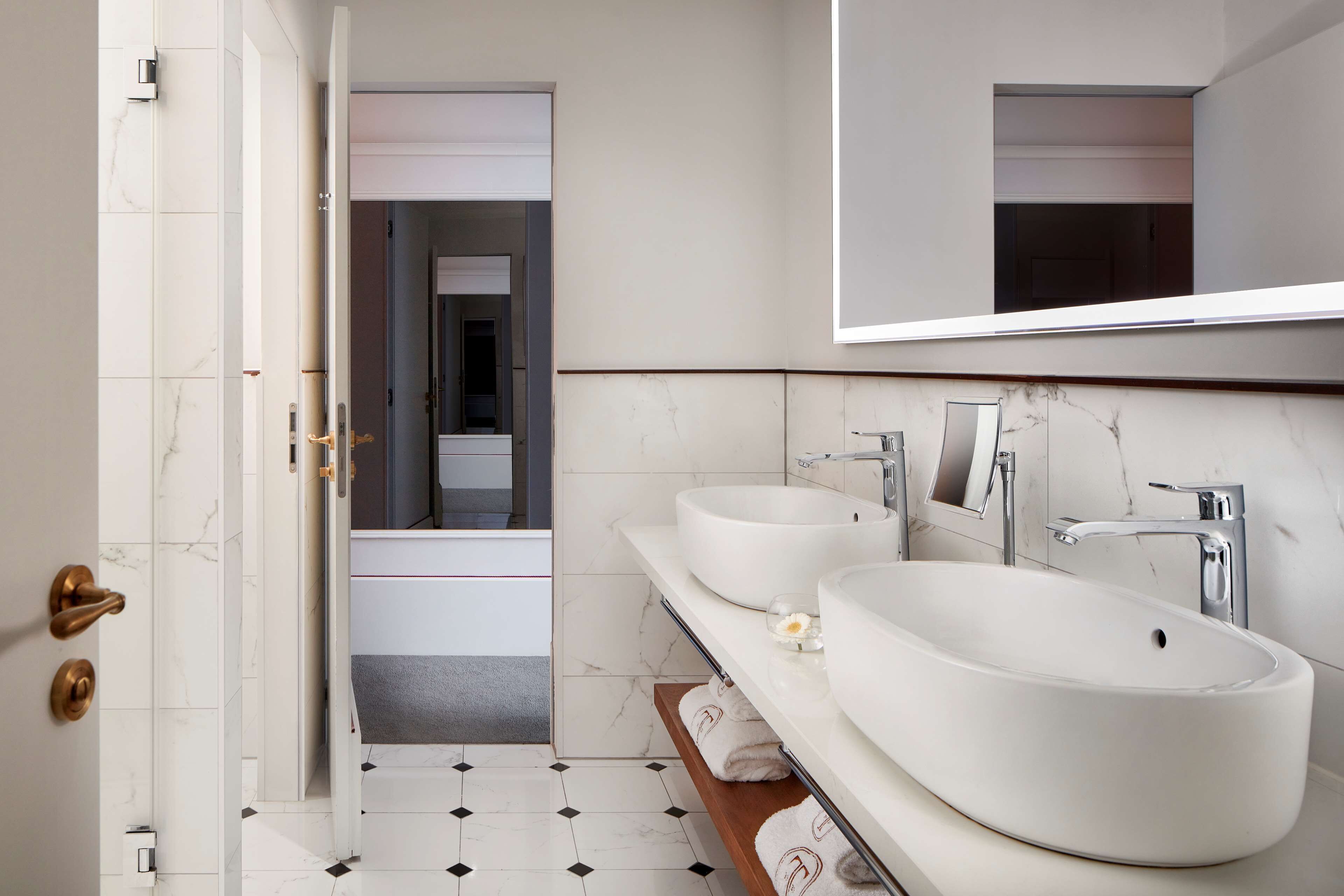 A modern bathroom with two sinks, a large mirror, and a shower area.