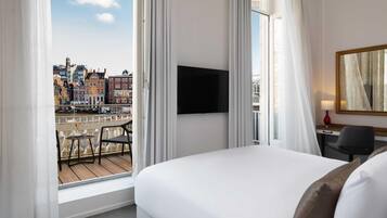 Habitación de hotel con cama, escritorio, silla, televisor y vistas a la ciudad.