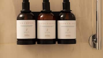 Trois bouteilles de produits de soins capillaires au thé vert sont posées sur un mur.