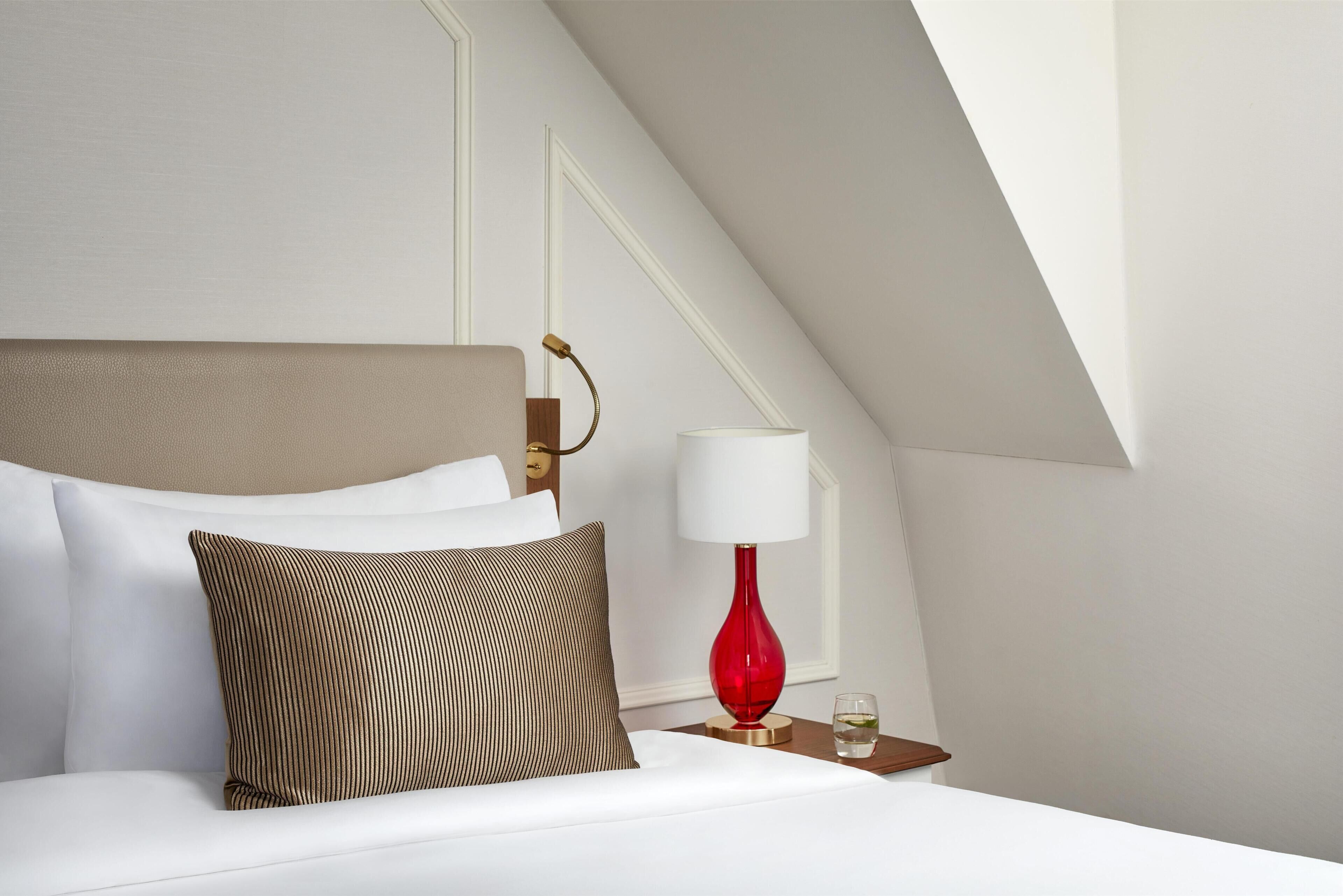Une chambre d’hôtel avec un lit, une lampe rouge et une table de chevet.