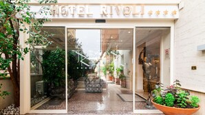 The entrance of HOTEL RIVOLI with a glass facade, potted plants, and a stone-tiled pathway leading inside. - Best Western Hotel Rivoli (Rome)