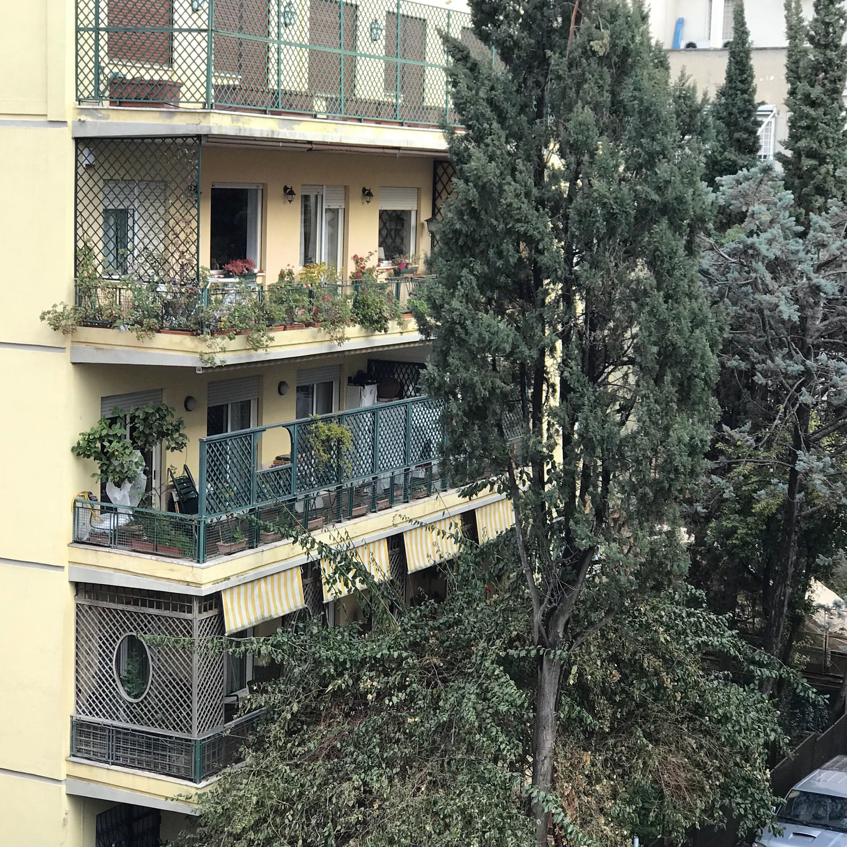 A multi-story building with balconies, some with plants.