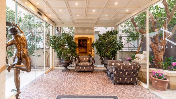 A covered outdoor area with a statue, patterned furniture, and potted plants. - Best Western Hotel Rivoli (Rome)