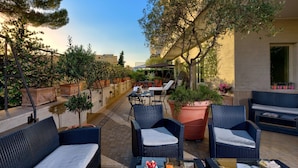 A rooftop patio with wicker furniture, potted plants, and a view of the cityscape. - Best Western Hotel Rivoli (Rome)