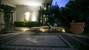 An outdoor patio area with a stone floor, seating, and potted plants.