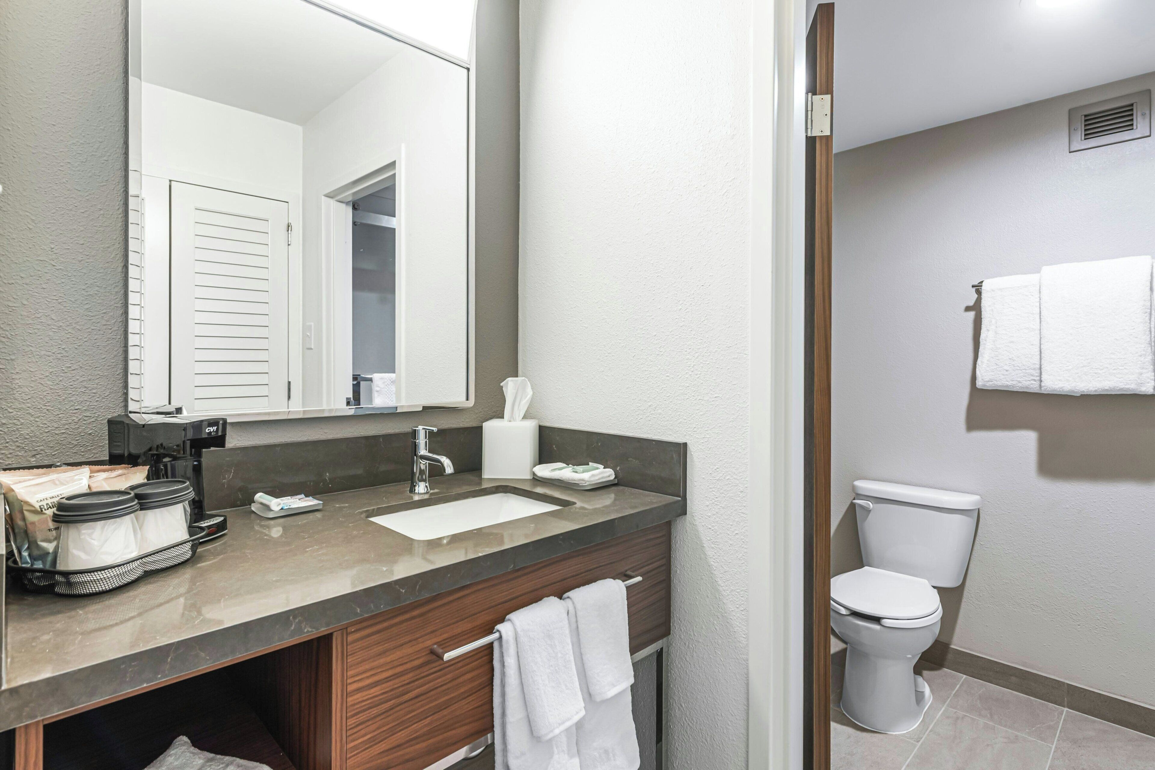 A bathroom with a sink, mirror, toilet, and towel rack.