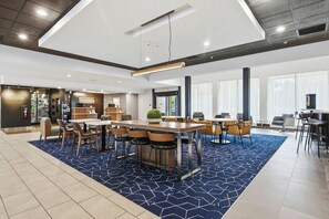 A modern hotel lobby with a reception desk, seating area, and a kitchenette. - Courtyard by Marriott Columbus (Columbus)