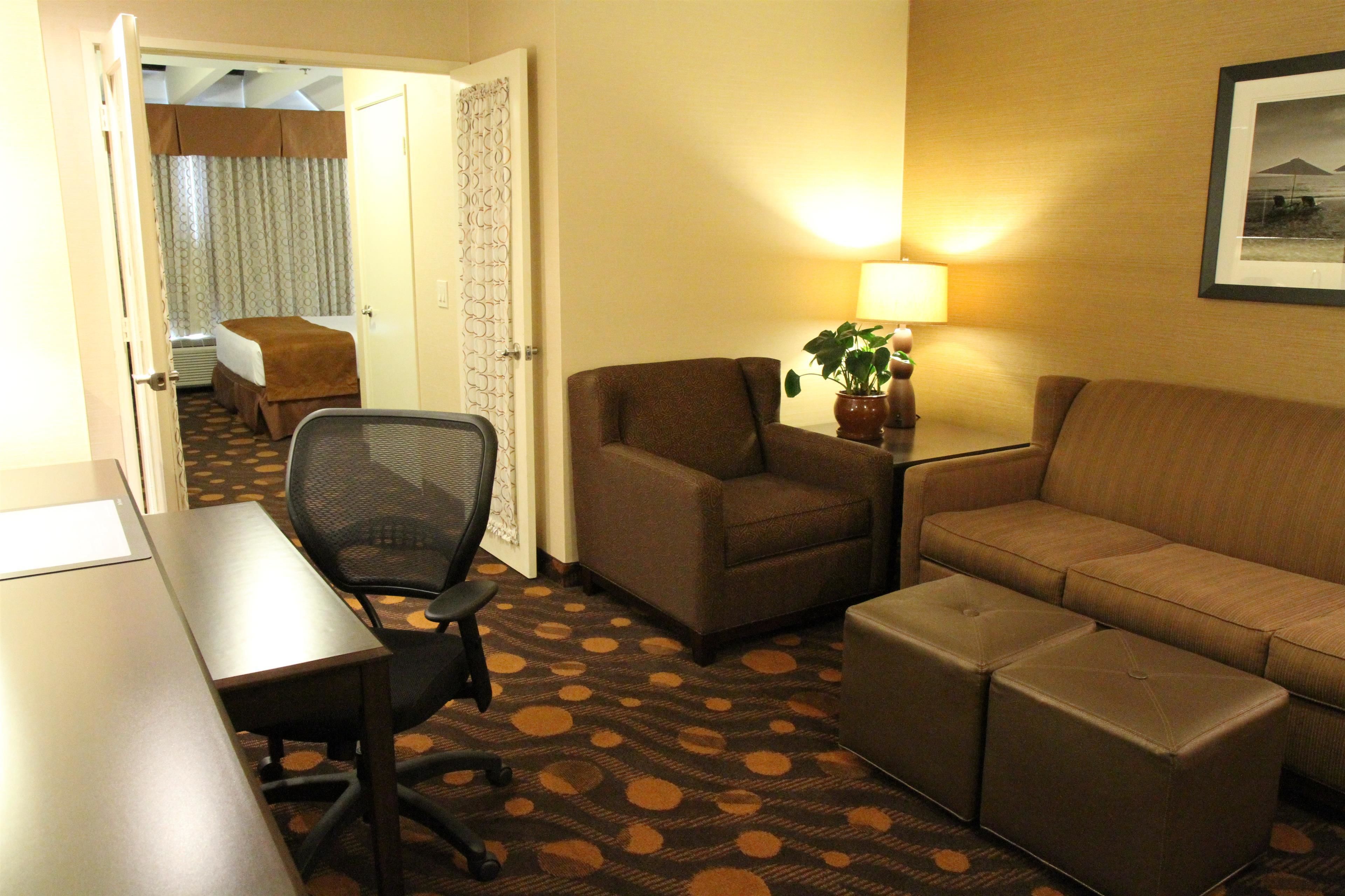 Une chambre d’hôtel comprenant un lit, un bureau, une chaise, un canapé et une petite table avec une lampe.