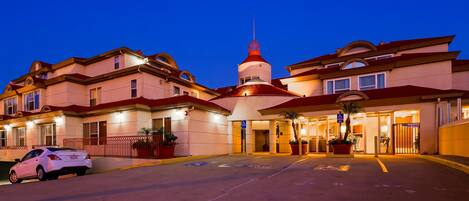 En hotelindgang med et parkeringsområde reserveret til handicapparkering og et skilt, der angiver parkeringsforbud.