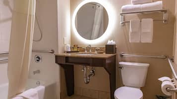 A bathroom with a bathtub, a sink with a mirror, a toilet, and a towel rack.