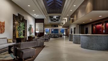 A hotel lobby with seating, a reception desk, and a large window.