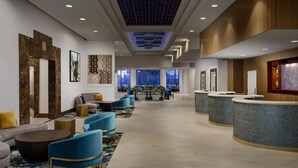 A hotel lobby with a reception desk, seating area, and artwork on the walls. - Hilton Charlotte University Place (Charlotte)