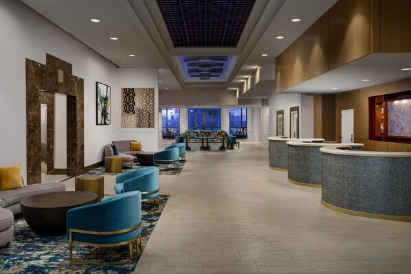 A hotel lobby with a reception desk, seating area, and artwork on the walls.