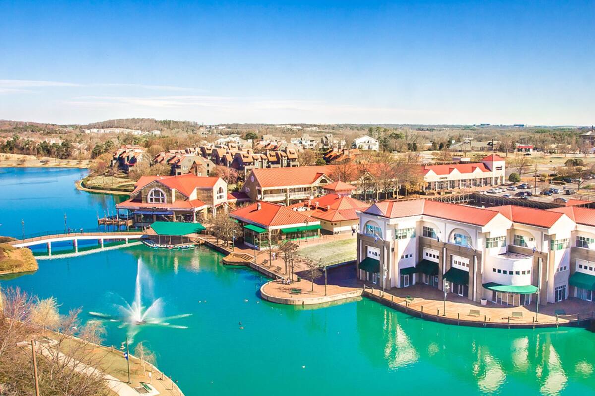 A lakeside hotel with a central courtyard, a bridge, and a fountain.