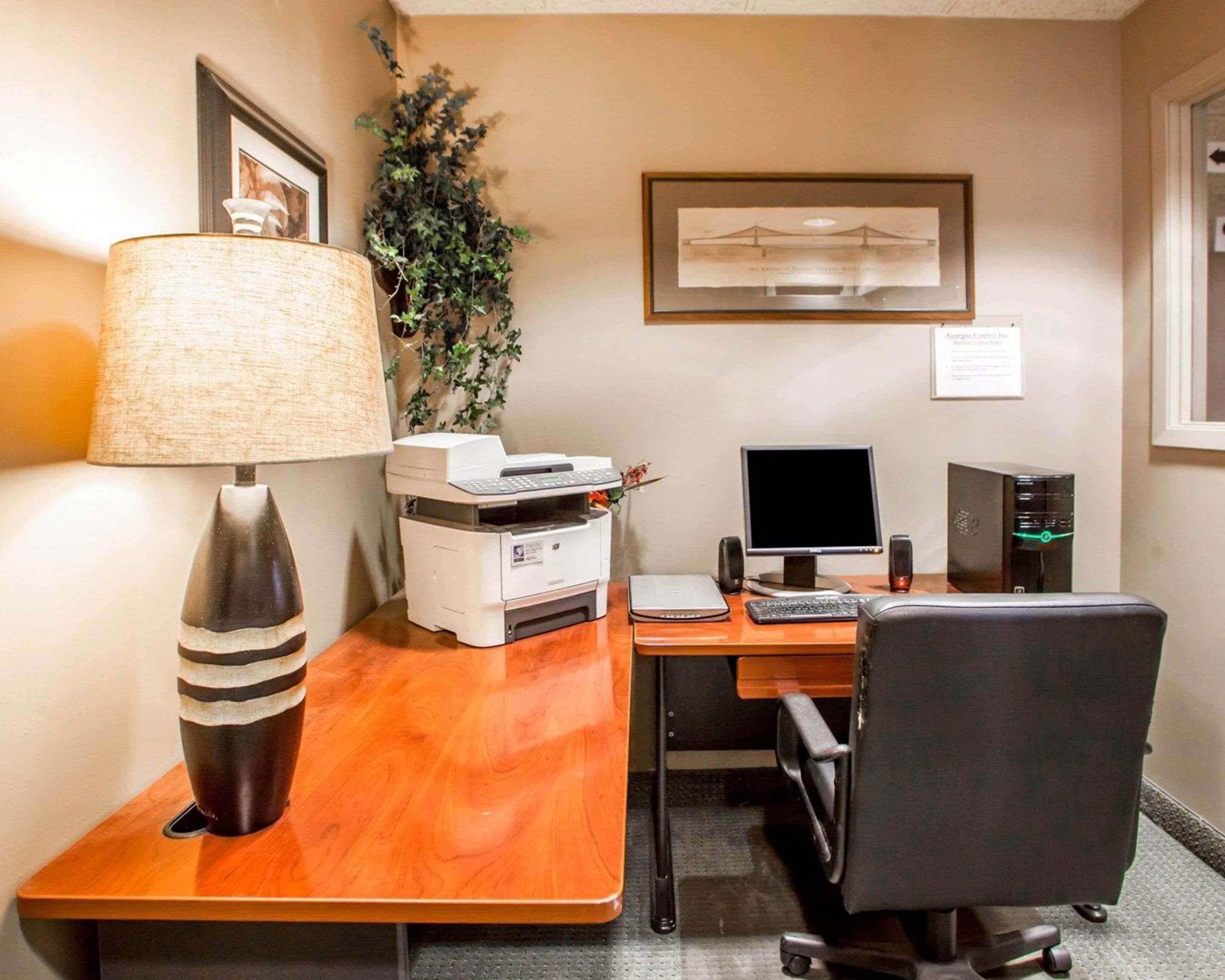 A hotel office with a desk, computer, printer, and a lamp.