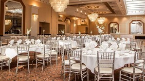 Un salón de banquetes con mesas redondas dispuestas para eventos, con candelabros y centros de mesa florales.