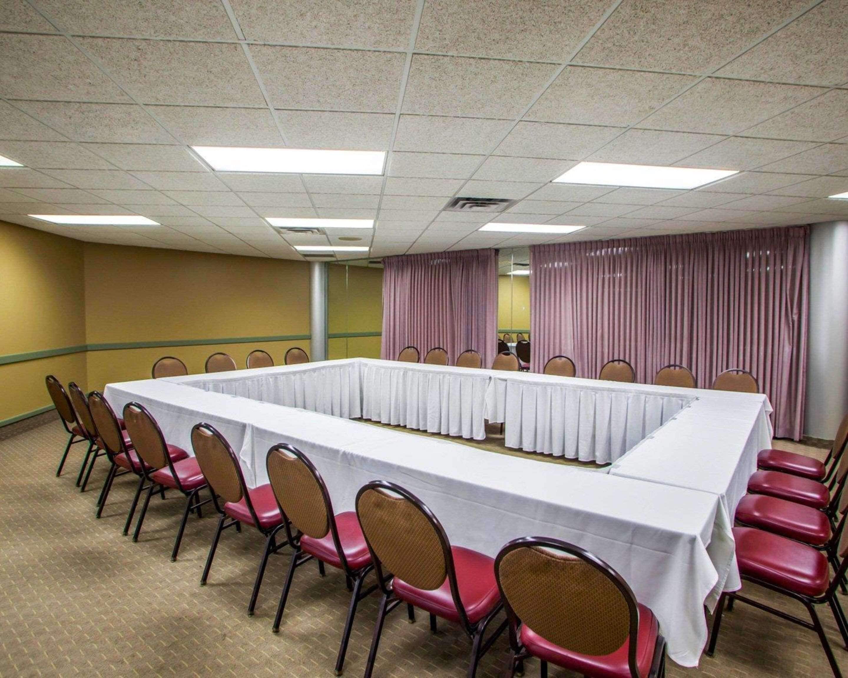A conference room with a long table and chairs, carpeted floor, and curtains.